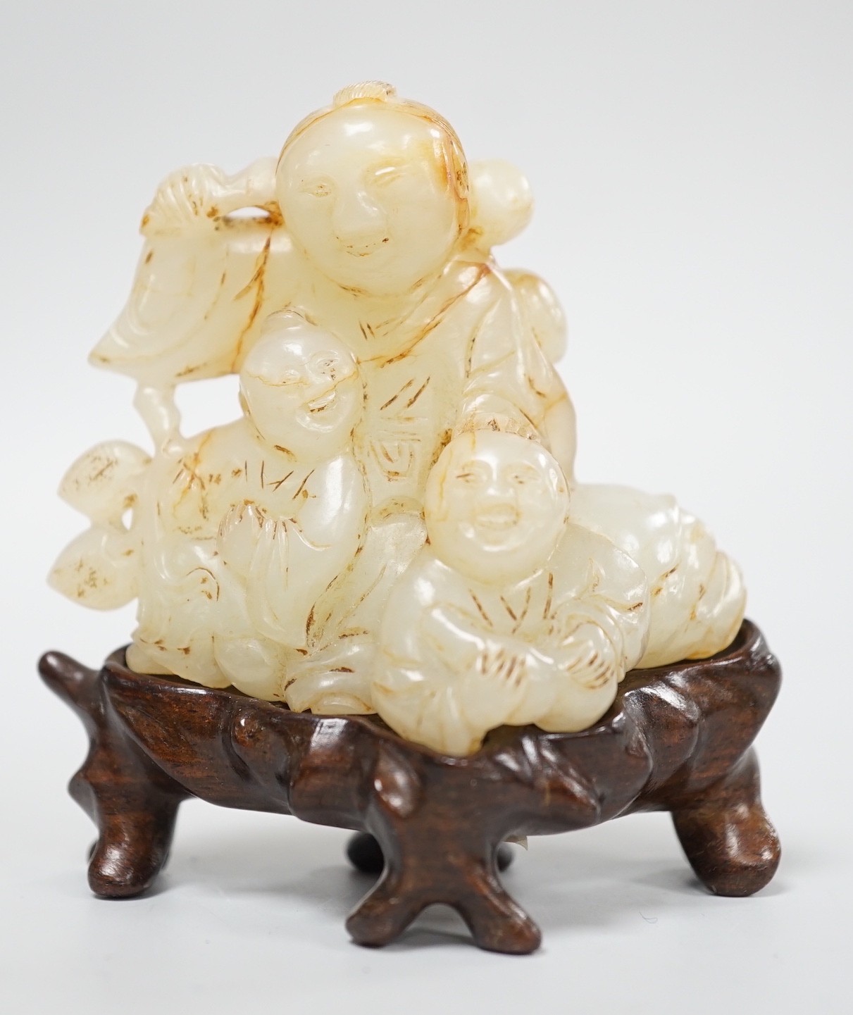 A Chinese white and russet jade group of three boys, 18th/19th century, 7.2 cm, wood stand